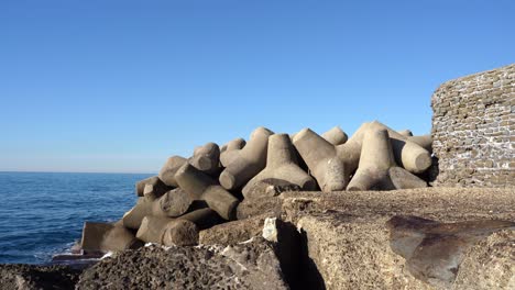 el muelle de la orilla del mar está lleno de enormes piedras de roca de forma triangular, fortificación de piedra contra poderosos rompeolas, olas e inundaciones. protección de la costa, obras defensivas en la playa del mar. poder de la naturaleza que conduce a la catástrofe