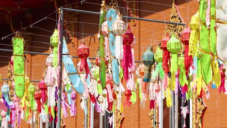 vibrant lanterns move in a breeze against a brick wall