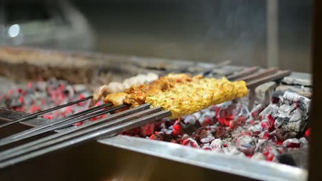 a man's hands rotating the skewers. shish kebab