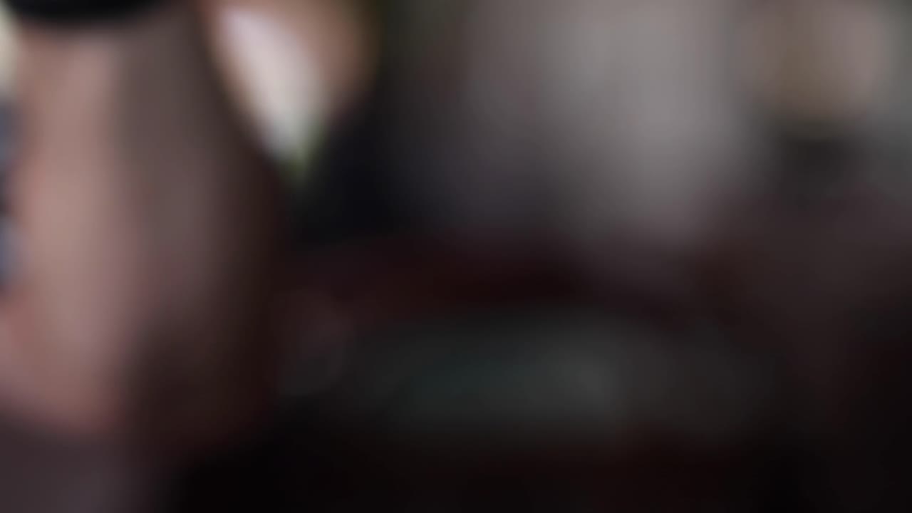 A hand delicately holds a chilled glass of white wine, showcasing condensation and elegant glassware.