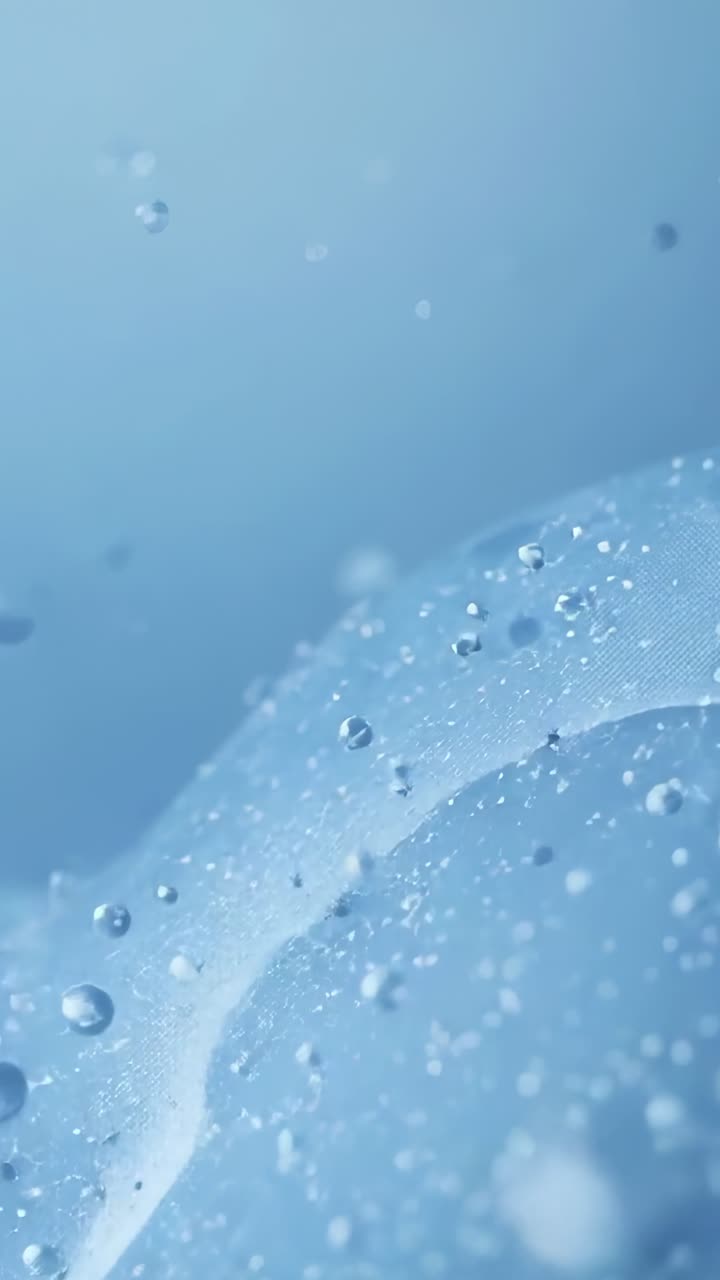 Vertical video: Zooming macro showing curved ribbon gathering droplets from tension, microbubbles