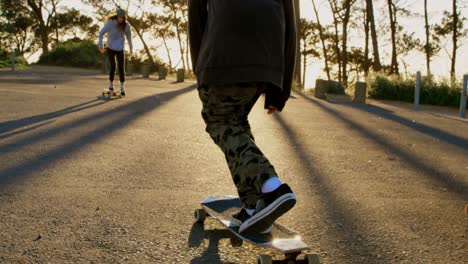 vista trasera de un joven patinador caucásico montando en patineta en una carretera de campo 4k