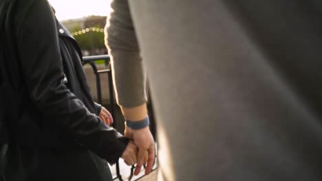 couple walking hand-in-hand on a bridge at sunset