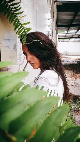 woman in an abandoned building, hidden by ferns