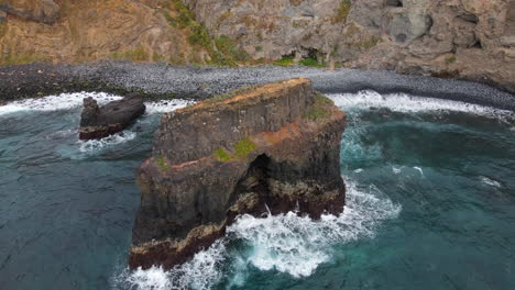playa de los rocas, tenerife: vista aérea en órbita de una de las dos formaciones rocosas y el mar golpeando la roca