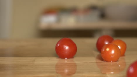 red cherry tomatoes fall on a cutting board with water splashes, apple prores slow-mo