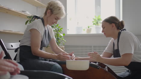 Caucasian girl teaches an elderly puppy to work on a potter&#039;s wheel. Assistance in the rehabilitation and adaptation of pensioners. Time-lapse filming of an elderly woman&#039;s potter&#039;s wheel