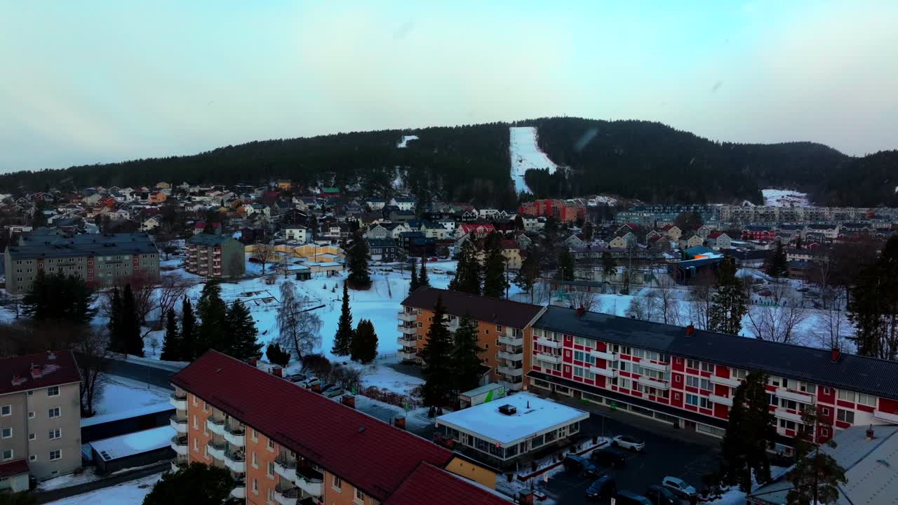 Tonsengagen Bjerke Arvoll Oslo skisenter, Norvegia, ripresa aerea con drone al mattino, nevicata con fiocchi di neve, fredda giornata invernale nuvolosa, cieli grigi, quartiere cittadino, edifici di appartamenti e condomini, verso il Circolo Polare Artico.