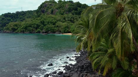 Drone-flyover-rocks-revealing-secluded-turquoise-colored-water-in-Principe-Island