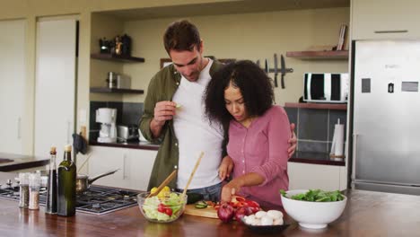Happy-diverse-couple-preparing-food-together-in-kitchen,-chopping-vegetables-for-salad