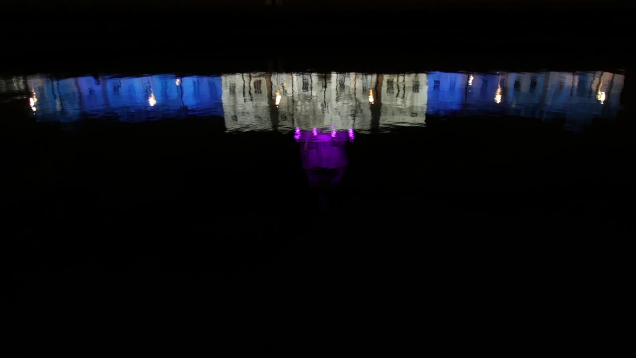 una toma serena de la casa de costumbre reflejada en el río liffey, con luces de invierno proyectándose en su fachada, creando una imagen de espejo vibrante y simétrica por la noche