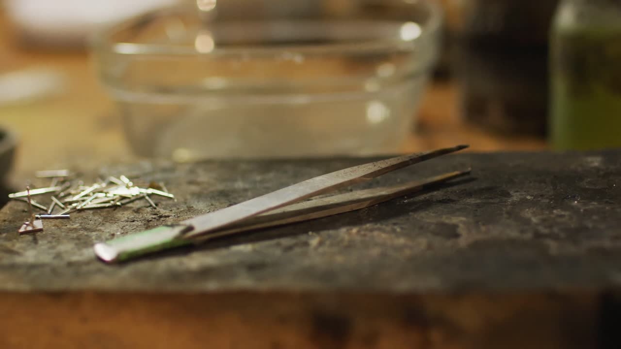 Close up of tweezers and jeweller tools lying on desk in workshop
