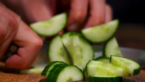 close up of a male hand cutting a pre cut cucumber into multiple pieces