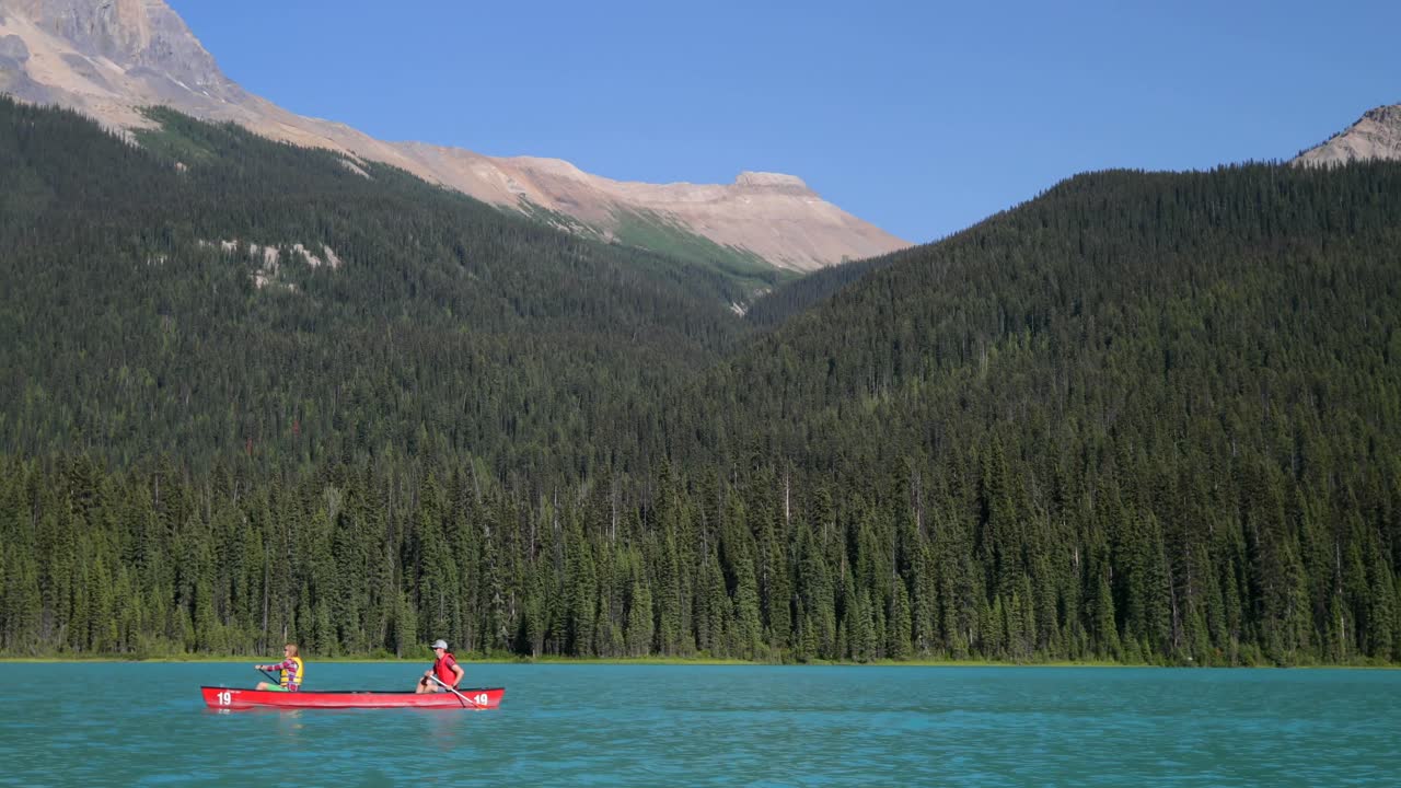 ⁇ 빛 4k에서 투르코이즈 강에서 젊은 부부 rowing 보트의 측면 뷰