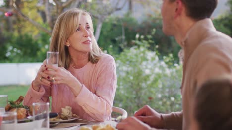 Video-of-happy-caucasian-senior-mother-and-adult-son-talking-at-outdoor-family-dinner-table