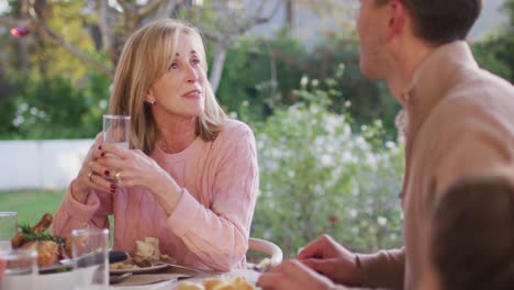 video of happy caucasian senior mother and adult son talking at outdoor family dinner table