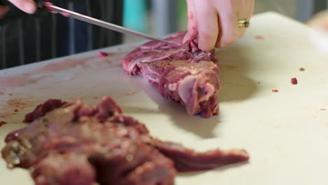 primer plano de ángulo bajo de carne de caza de venado cortada de los huesos con un cuchillo afilado