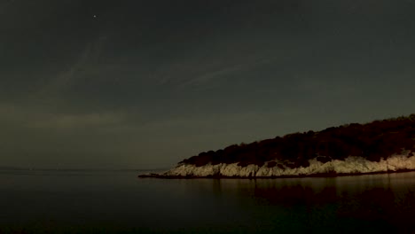 serene twilight over a calm sea with a dark silhouette of a forested coastline