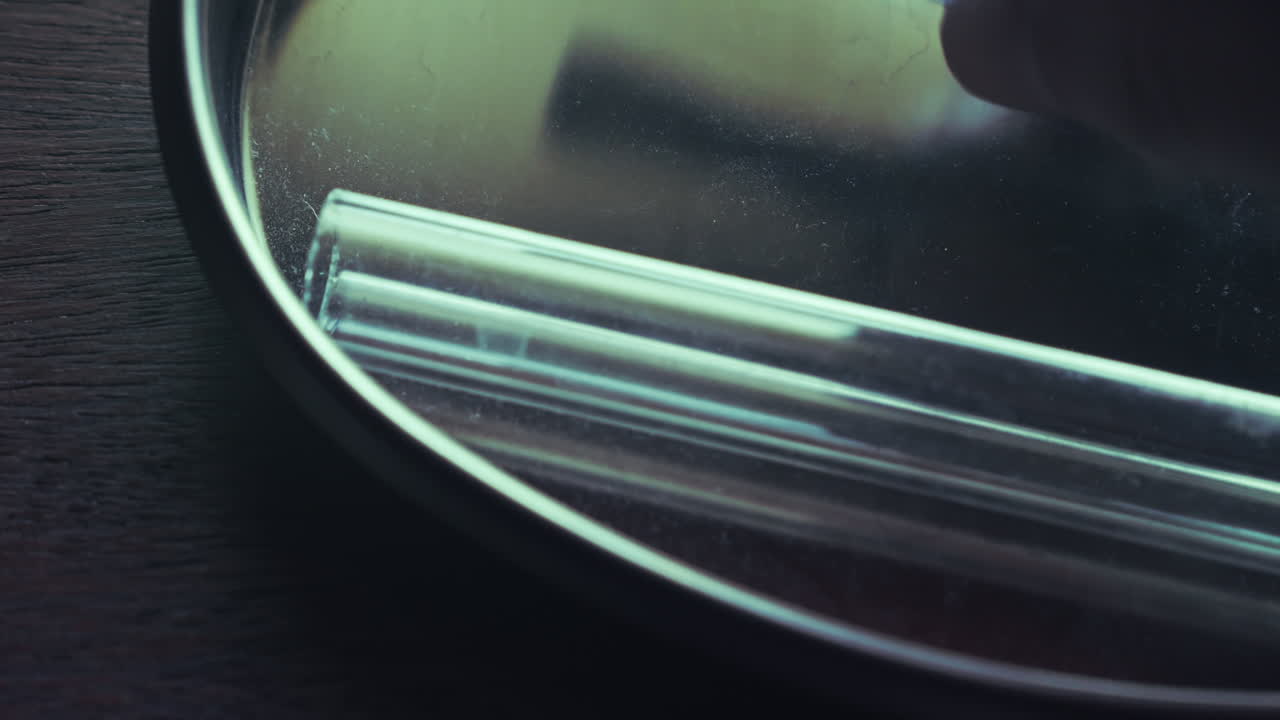 Extreme close-up van glazen ampullen en een pincet die van een medisch dienblad worden getild. Roept thema's op van vaccinatie, laboratoriumonderzoek en klinische proeven.