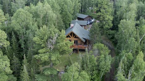 Aerial-pullback,-lakeside-forest-wooden-cabin-during-the-day