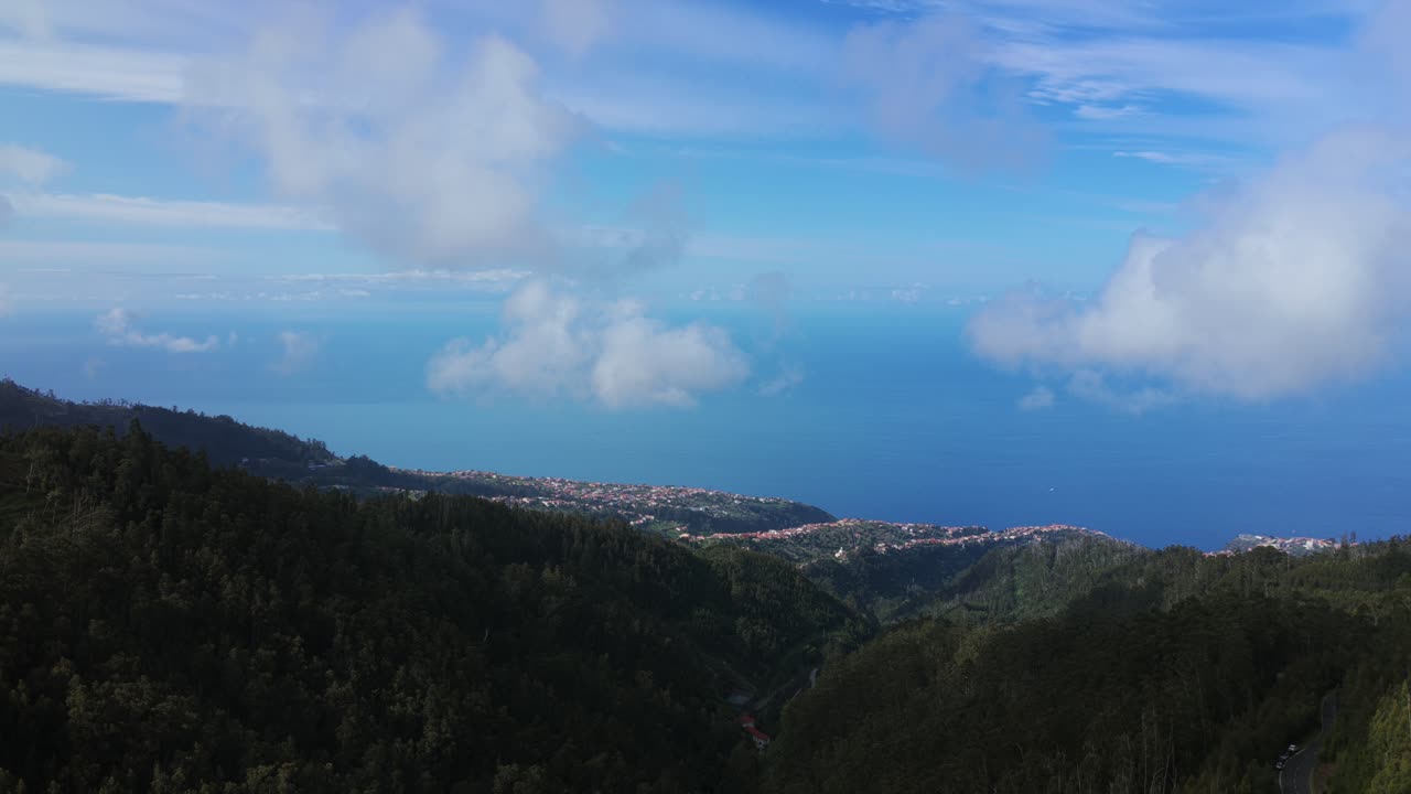 Drone flies over lush green mountains from Pico Fernandes, coastline and Atlantic Ocean in background. Madeira, Portugal. Aerial forward, copy space