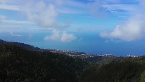 drone flies over lush green mountains from pico fernandes, coastline and atlantic ocean in background. madeira, portugal. aerial forward, copy space