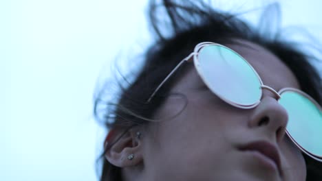 young woman posing with big fun sunglasses looking at horizon