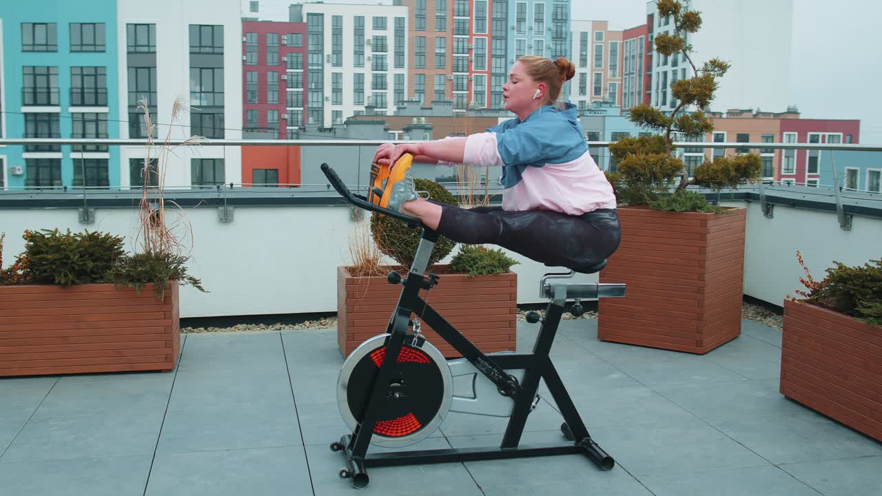 백인 여성 코치가 야외에서 정지 자전거에서 스트레칭 에어로빅 훈련 연습을 하고 있습니다.