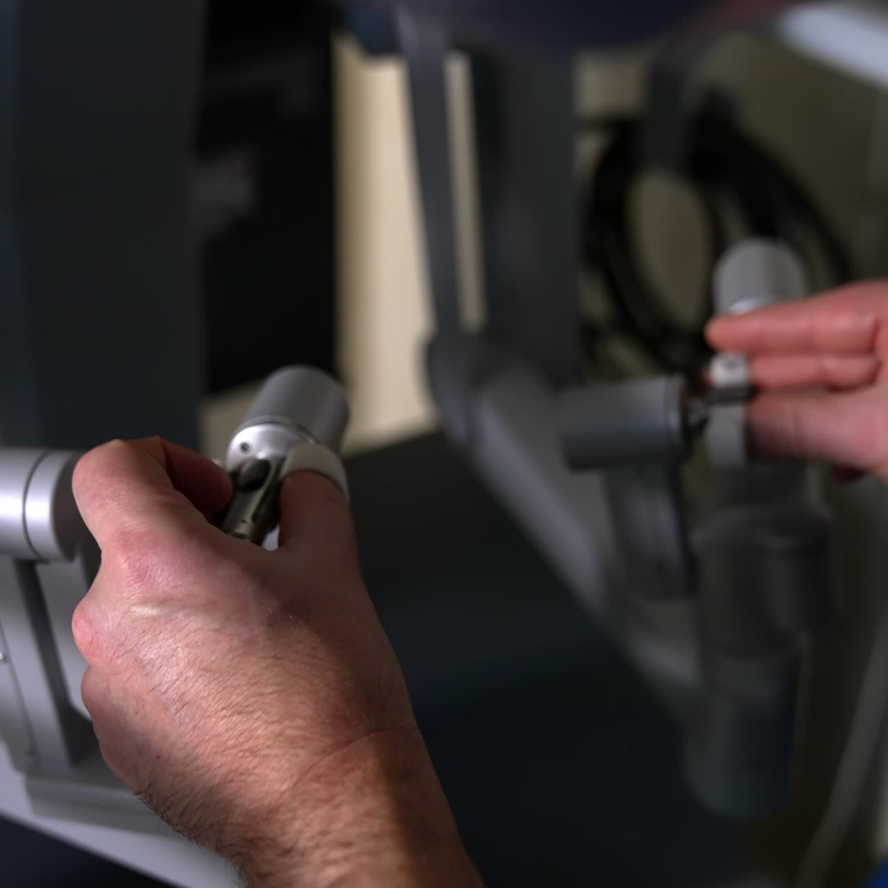 Male doctor's hands moving the handles of robotic surgeon system. Close up. Professional operates Da Vinci machine