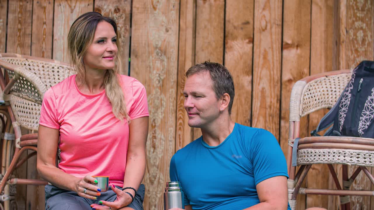 Close up: young happy Caucasian couple sitting outside drinking coffee