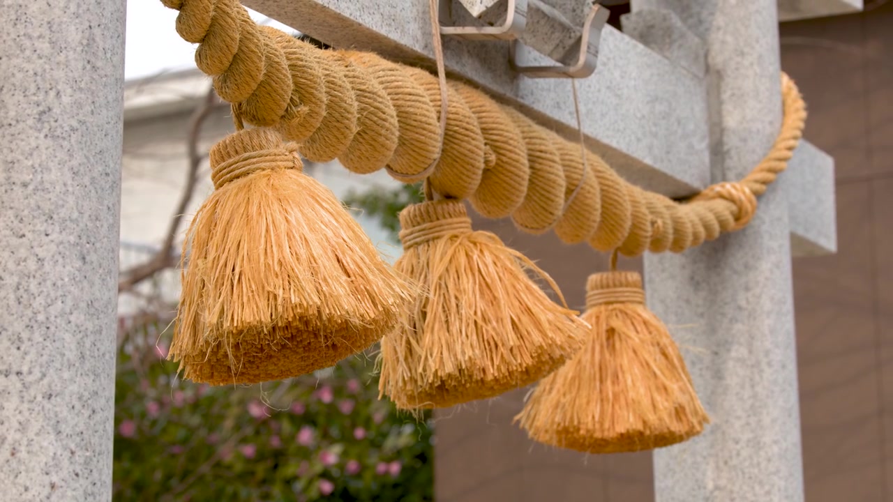 日本の神社にある石の鳥居の伝統的な藁の房に人が触れている。
