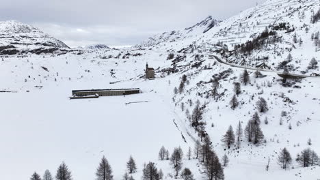 old spittel at the black asphalt road over the with snow covered simplon pass on a cloudy day