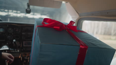 man puts hand on large blue present box with red ribbon