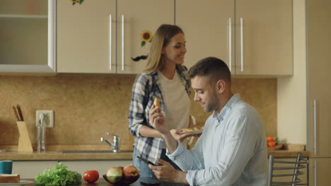 couple kissing and eating breakfast in kitchen