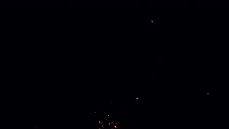 las brasas rojas calientes de una fogata parecen ser succionadas desde el oscuro cielo nocturno hacia el suelo