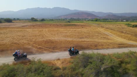 atvs drive through kos countryside, tracking aerial side view