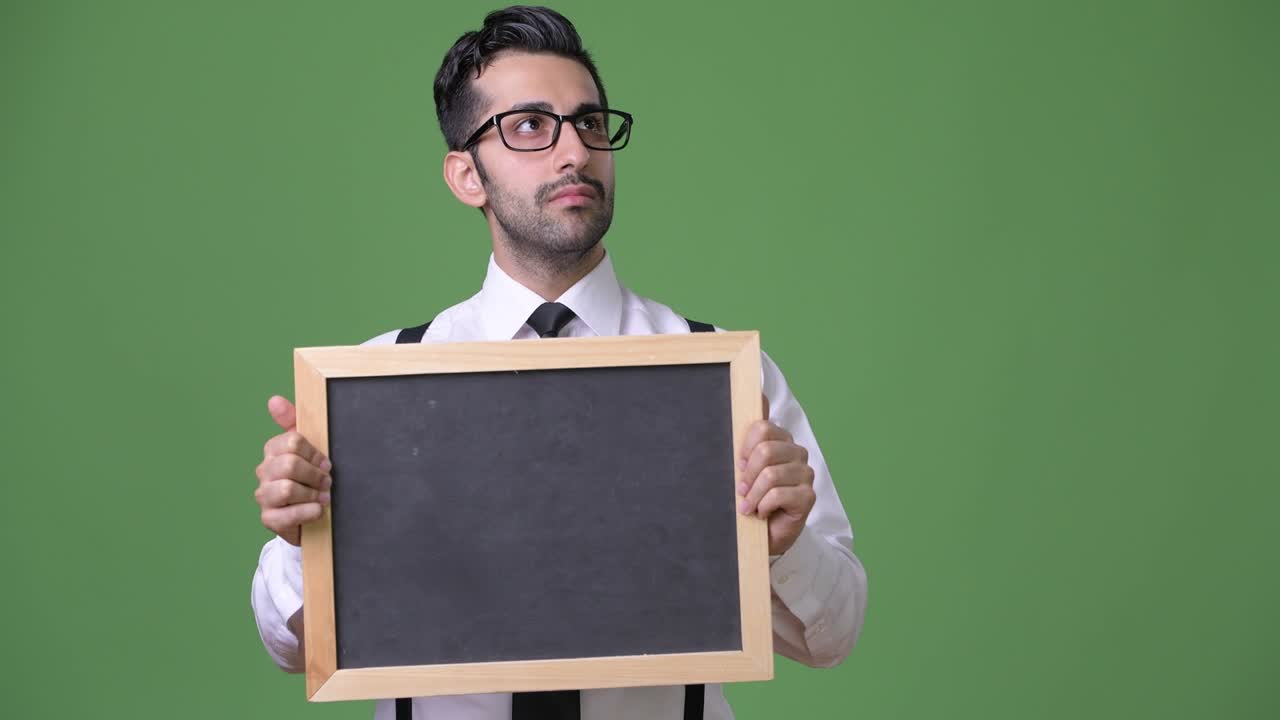 joven empresario persa barbudo y guapo contra un fondo verde