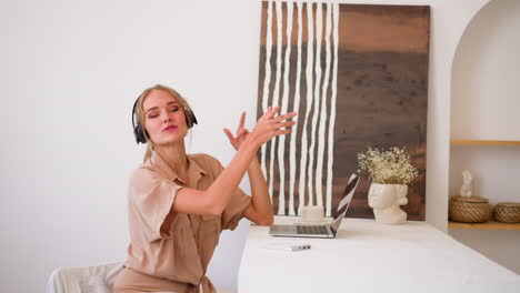 Happy-woman-enjoys-music-and-throws-paper-sitting-at-table