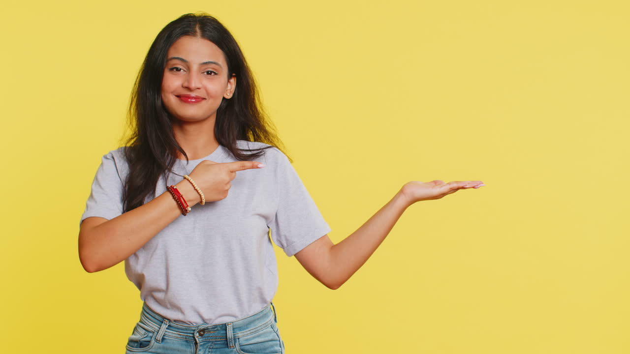 mujer joven mostrando los pulgares hacia arriba y apuntando a la derecha en el espacio en blanco lugar para su logotipo de publicidad