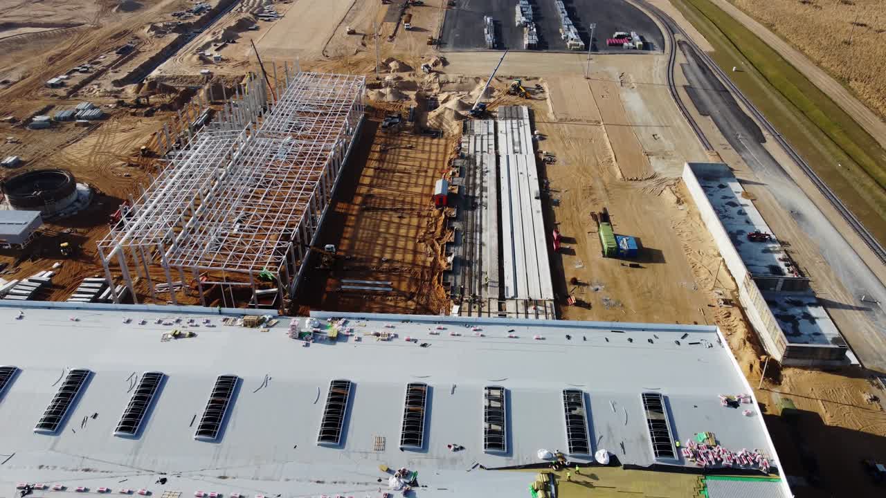 vuelo aéreo de drones sobre un nuevo sitio de desarrollo de construcciones proyectos de almacenes y maquinaria pesada y trabajadores de la construcción están trabajando en la zona.