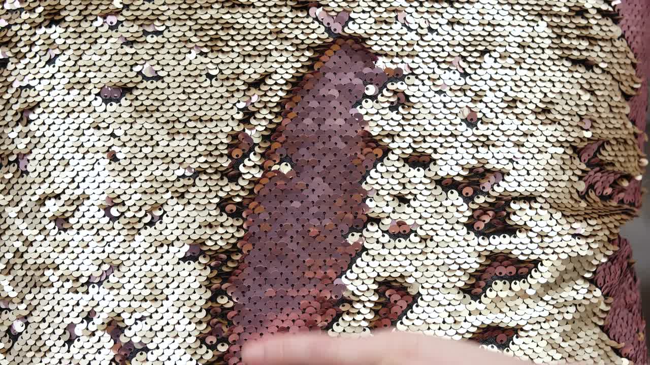 la mano acaricia las pañuelas doradas redondas de cerca la mano toca una superficie de almohada de pañuelos dorados de textura brillante escamas de textura meditativa hipnótica de pañuelas redondas con transición