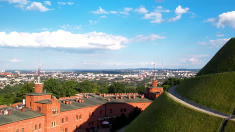 Ascending-aerial-shot-showing-beautiful-city-of-Krakow-during-sunny-day-with-blue-sky-surrounded-by-green-park-trees---KoÅ›ciuszko-Mound-Sight