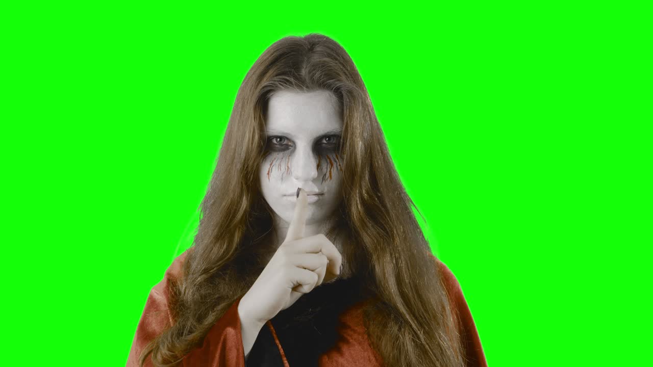 Shhh! - Ragazza adolescente, travestita per Halloween o una festa in maschera, davanti a uno schermo verde
