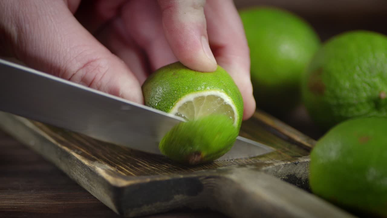 las manos de los hombres cortan un limón jugoso en una tabla de cortar.