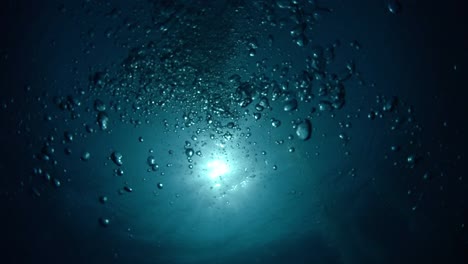 underwater looking up to the sun-ball with air bubbles rising to the surface