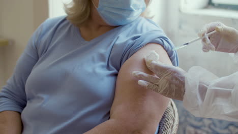 Medium-shot-of-doctor-vaccinating-woman-against-covid-at-home