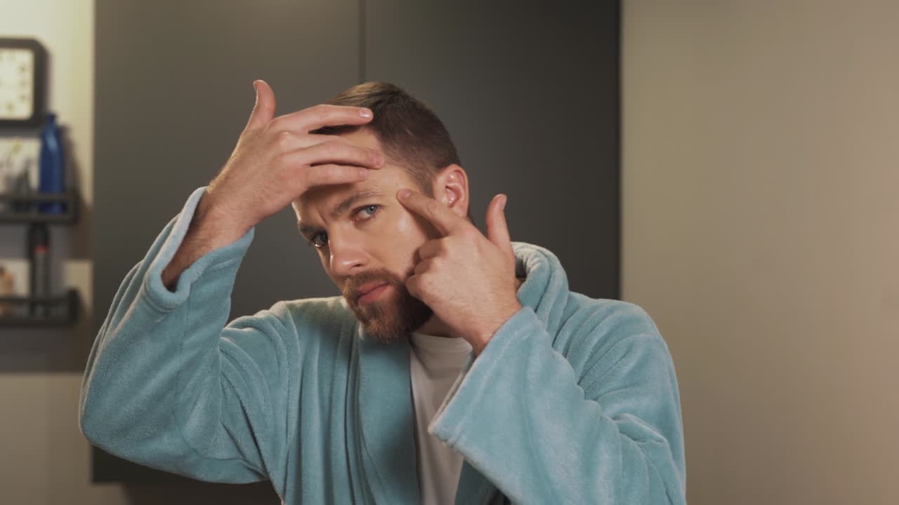 retrato de un hombre molesto que examina la piel problemática de su cara