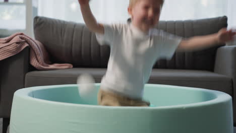 Excited-little-blond-boy-prepares-and-jumps-into-ball-pool