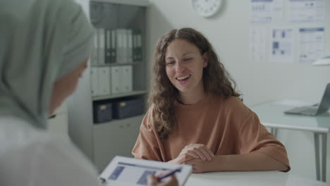 Woman Talking to Female Doctor in Hijab during Medical Consultation in Clinic