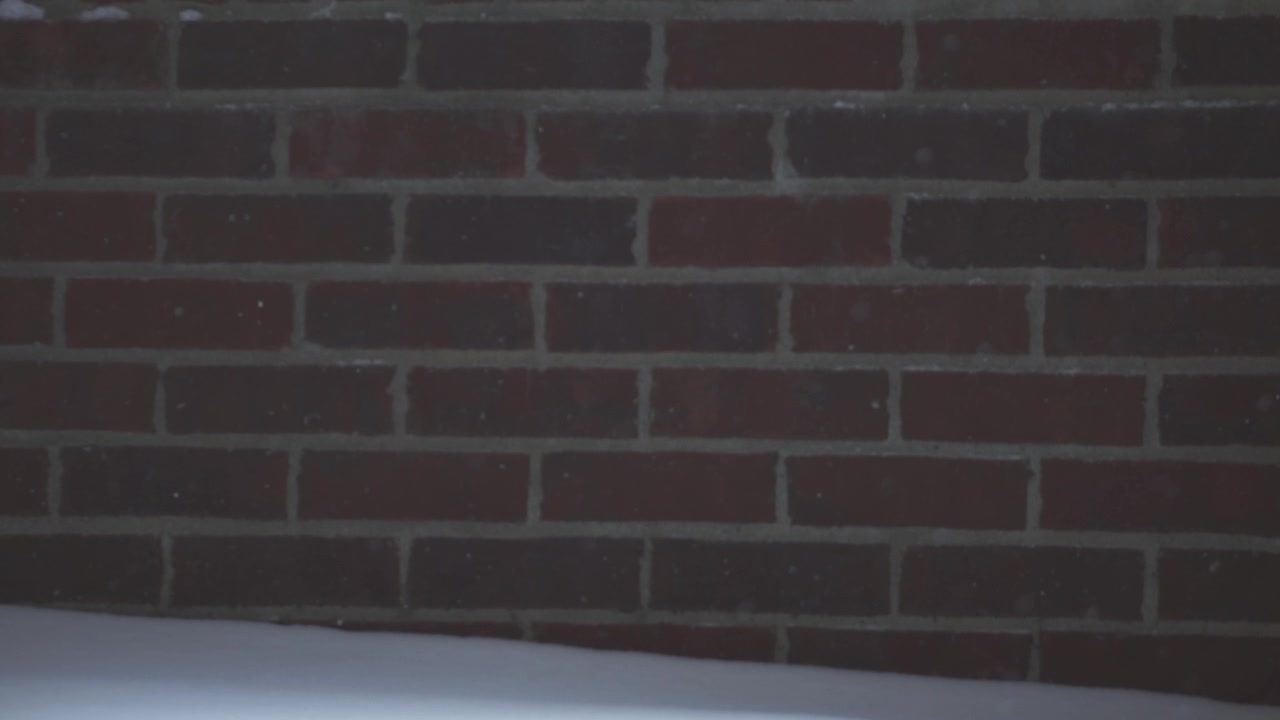 Snow Falling Against a Red Brick Wall